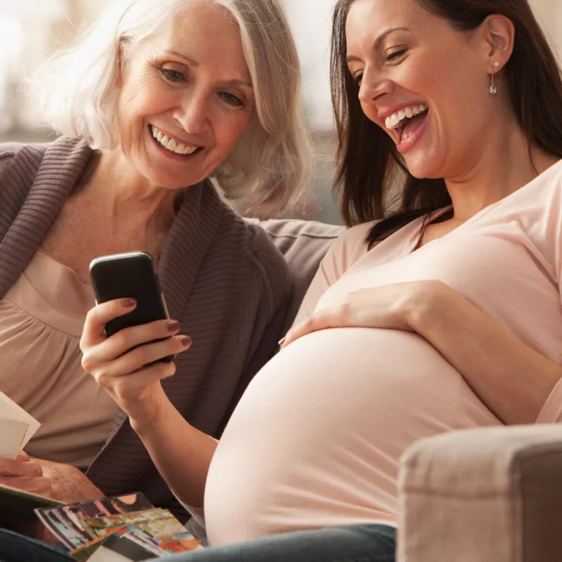 A pregnant woman with her mom looking something on her cell phone